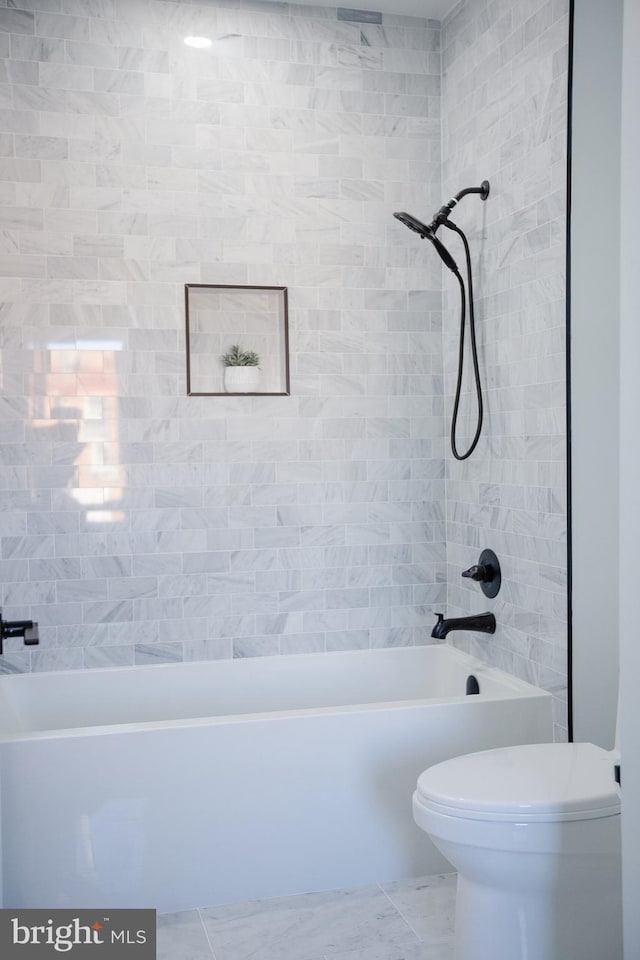 bathroom featuring tile flooring, toilet, and tiled shower / bath