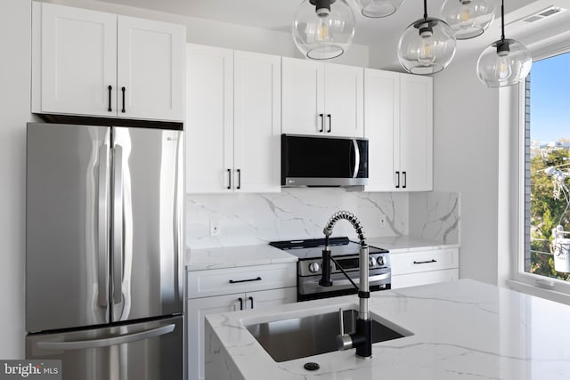 kitchen with appliances with stainless steel finishes, light stone counters, and white cabinets