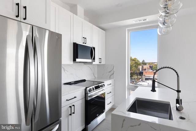 kitchen with stainless steel appliances, tasteful backsplash, white cabinetry, light stone counters, and sink