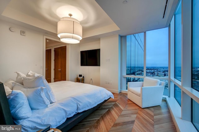 bedroom featuring light parquet floors and a raised ceiling