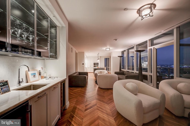 kitchen with decorative light fixtures, dark parquet floors, sink, and light stone countertops