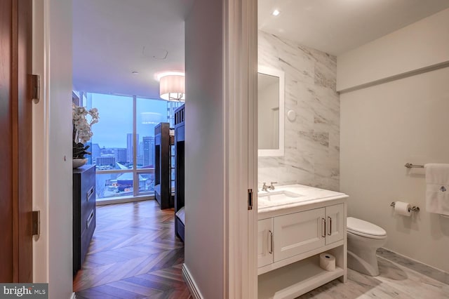 bathroom with tile walls, floor to ceiling windows, vanity, and parquet flooring