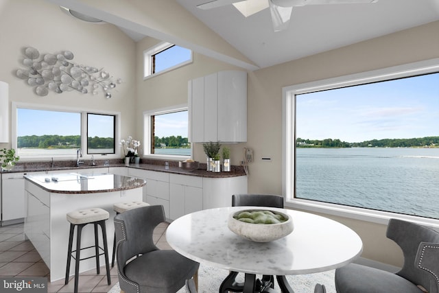 kitchen with ceiling fan, a kitchen island, white cabinetry, and light tile floors