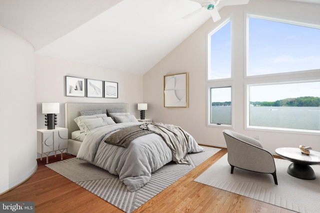 bedroom featuring a water view, hardwood / wood-style floors, ceiling fan, and high vaulted ceiling