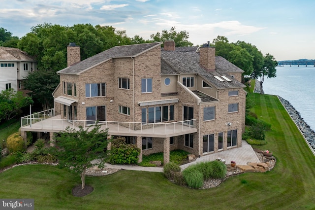 rear view of property featuring a lawn and a water view