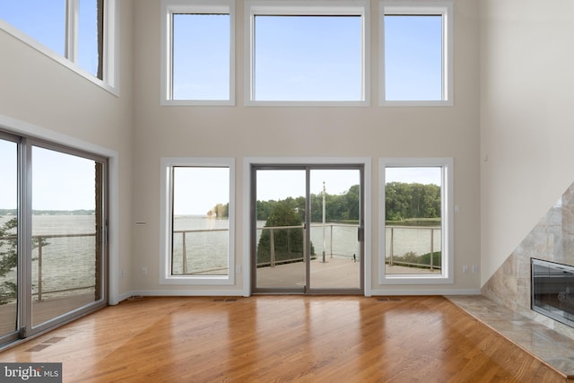 unfurnished living room featuring light hardwood / wood-style flooring, a high end fireplace, and plenty of natural light