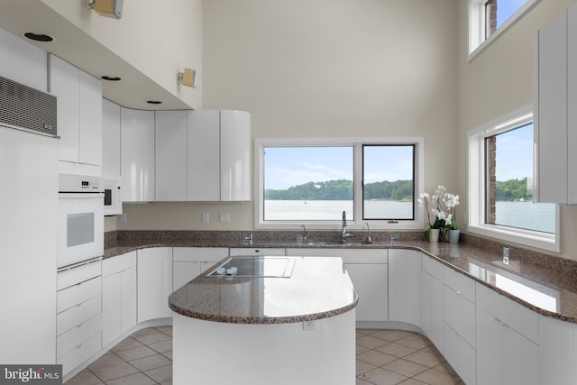 kitchen featuring white appliances, plenty of natural light, and light tile floors