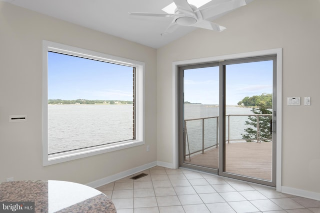 interior space featuring vaulted ceiling, ceiling fan, light tile flooring, and a water view