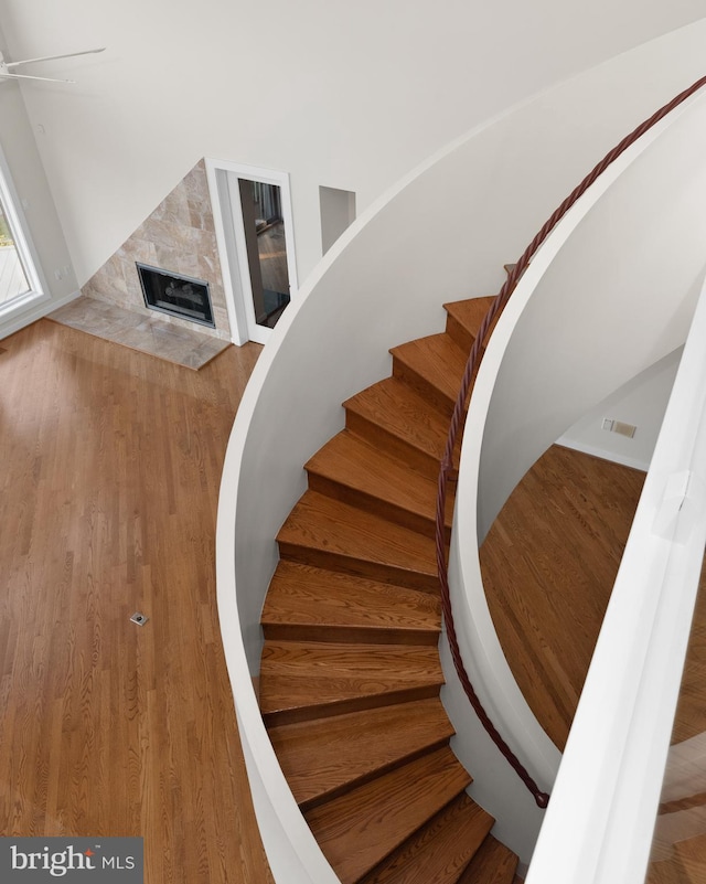 staircase featuring a high end fireplace and wood-type flooring