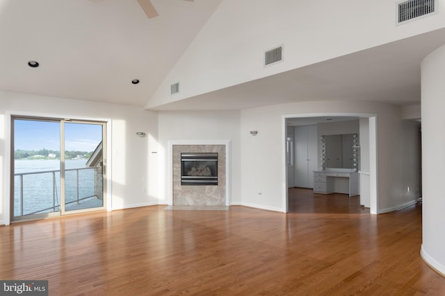 unfurnished living room with high vaulted ceiling, a tile fireplace, and dark wood-type flooring