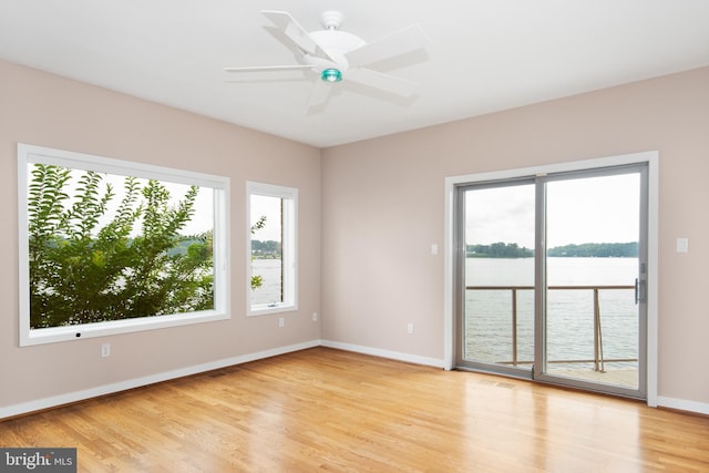 unfurnished room featuring ceiling fan, light wood-type flooring, and a healthy amount of sunlight