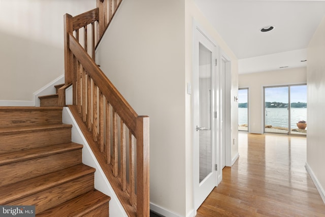 stairs featuring a water view and light wood-type flooring