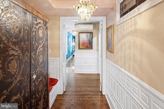 corridor with a notable chandelier, a raised ceiling, dark hardwood / wood-style floors, and a wall mounted AC