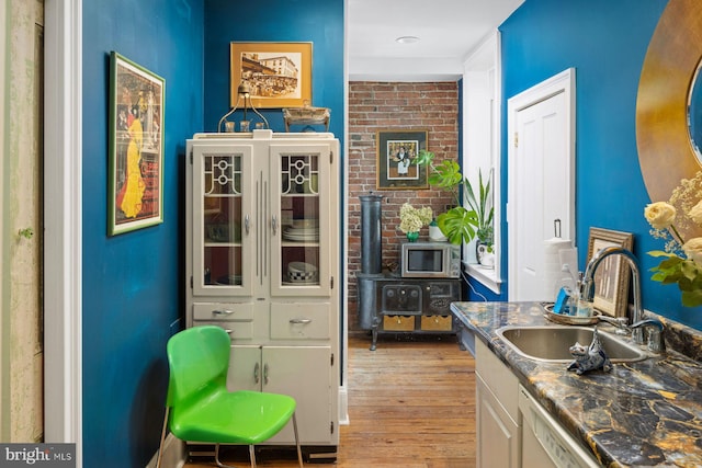 interior space featuring a fireplace, light hardwood / wood-style flooring, white cabinets, stainless steel microwave, and sink