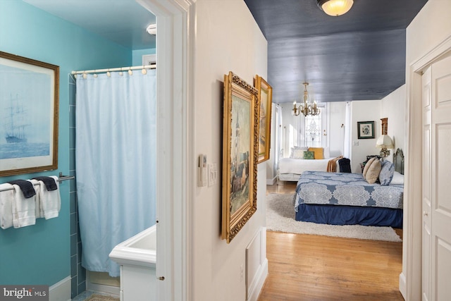 bedroom with light hardwood / wood-style flooring and a notable chandelier