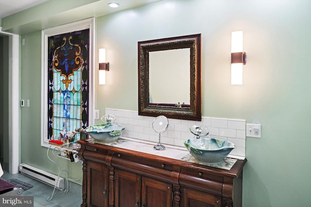 bathroom with dual bowl vanity, baseboard heating, tasteful backsplash, and tile floors