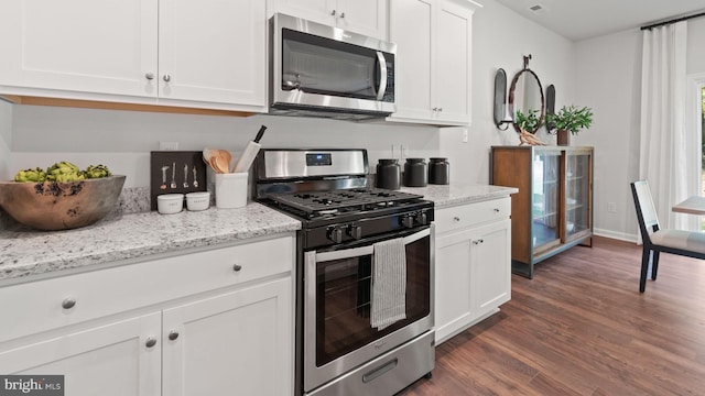 kitchen with stainless steel appliances, dark wood-type flooring, light stone counters, and white cabinets