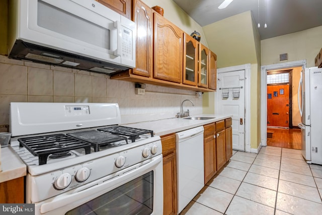 kitchen featuring white appliances, sink, and light tile floors