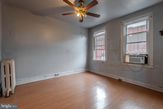 empty room with ceiling fan, radiator, and light hardwood / wood-style flooring