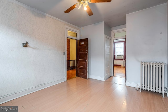 unfurnished room with radiator heating unit, ceiling fan, and light wood-type flooring