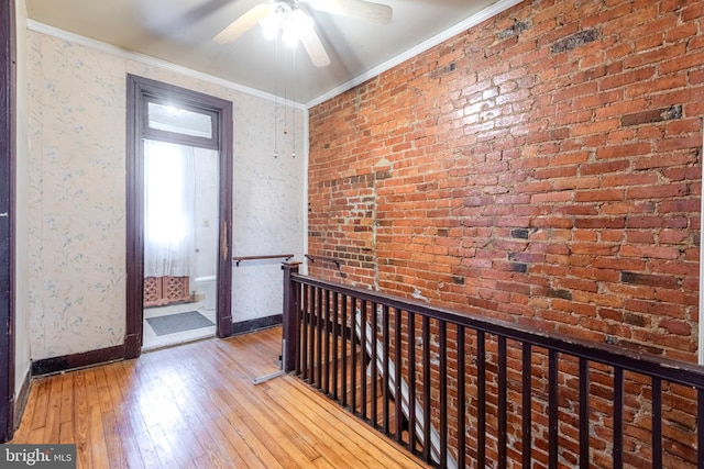 hallway with crown molding, light hardwood / wood-style floors, and brick wall