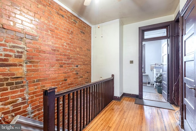 hallway featuring brick wall and light wood-type flooring