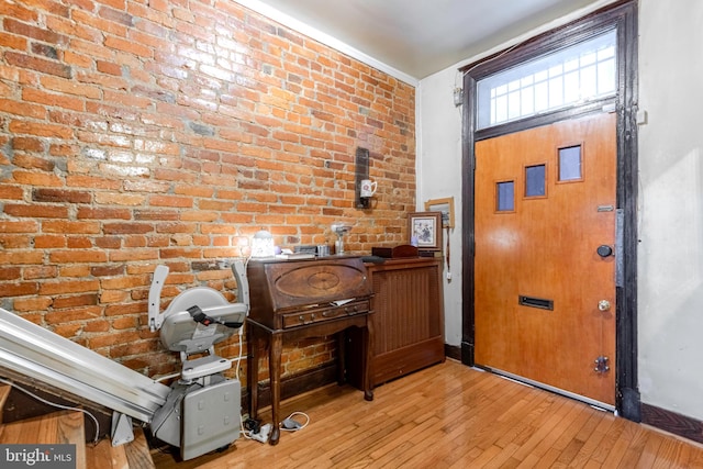 entryway featuring brick wall and light hardwood / wood-style floors