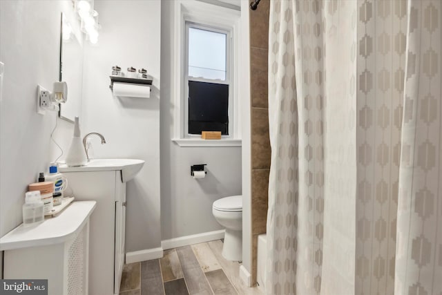 bathroom with toilet, vanity, and wood-type flooring