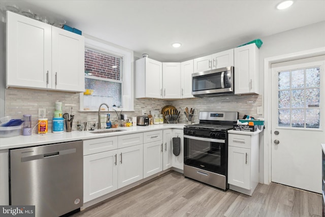 kitchen with white cabinets, light hardwood / wood-style floors, sink, and stainless steel appliances