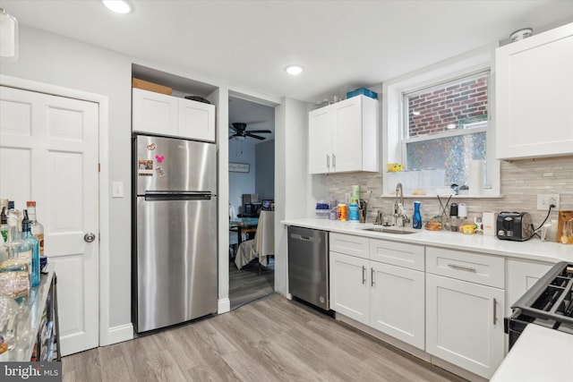 kitchen featuring appliances with stainless steel finishes, tasteful backsplash, light hardwood / wood-style floors, white cabinetry, and ceiling fan