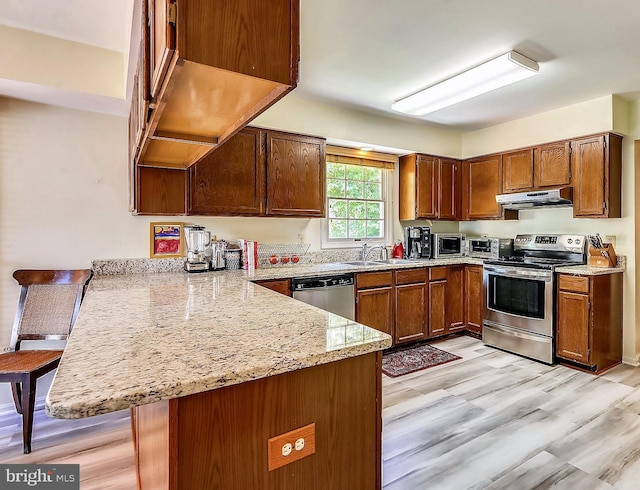 kitchen with sink, stainless steel appliances, kitchen peninsula, and a kitchen bar