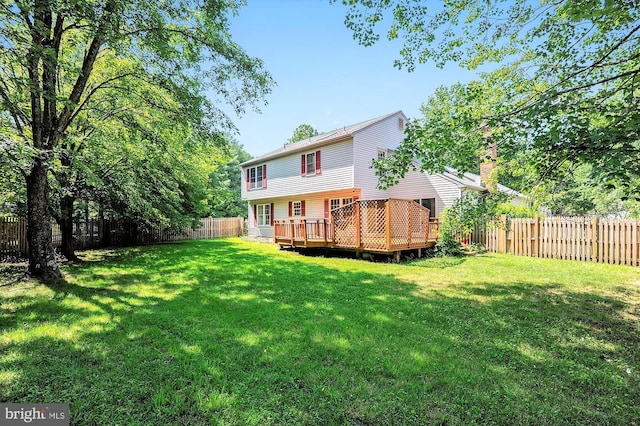 rear view of house with a wooden deck and a lawn