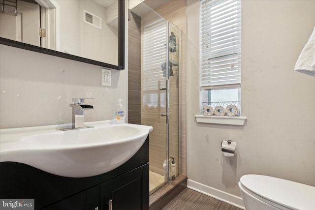 bathroom with hardwood / wood-style floors, vanity, toilet, and a shower with door