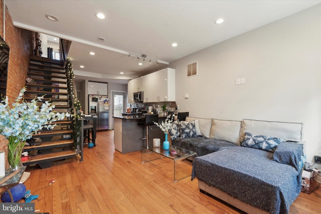 living room featuring rail lighting and light hardwood / wood-style flooring