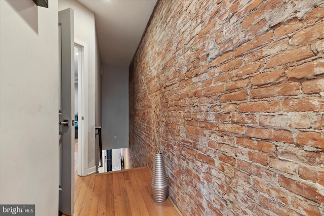 hall featuring brick wall and hardwood / wood-style flooring