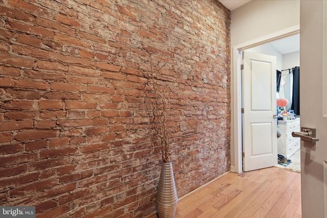 hall featuring brick wall and light hardwood / wood-style flooring