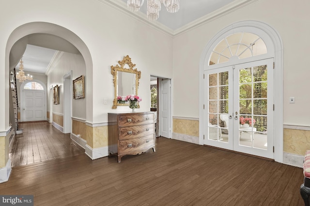 entryway with a chandelier, dark wood-type flooring, french doors, and crown molding