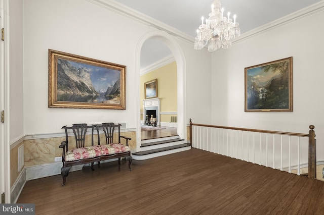 living area featuring dark hardwood / wood-style flooring, ornamental molding, and a chandelier