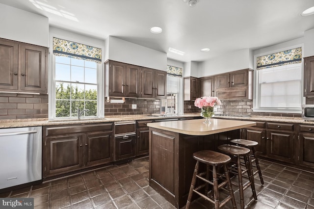 kitchen with dark tile floors, sink, a kitchen island, appliances with stainless steel finishes, and dark brown cabinetry