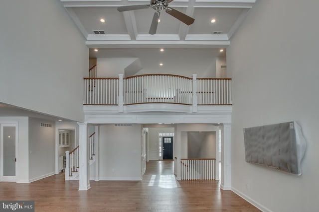 interior space featuring beam ceiling, decorative columns, ceiling fan, and hardwood / wood-style flooring