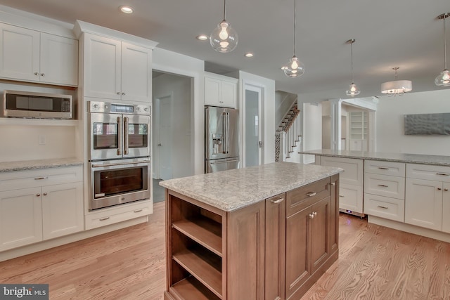 kitchen with hanging light fixtures, light hardwood / wood-style floors, and stainless steel appliances