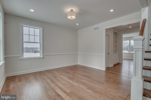 spare room featuring light wood-type flooring and ornate columns