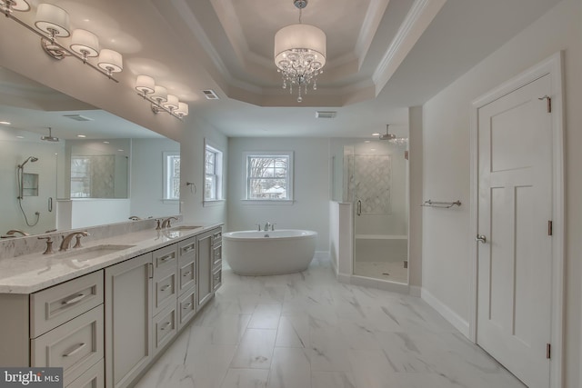 bathroom with tile floors, ceiling fan with notable chandelier, double sink vanity, shower with separate bathtub, and a tray ceiling