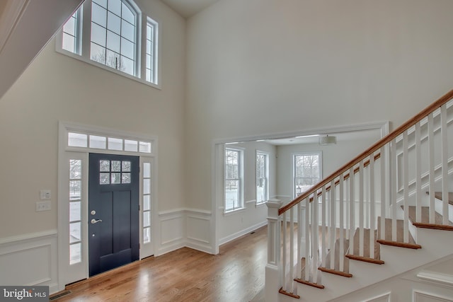 foyer entrance with light wood-type flooring and a towering ceiling