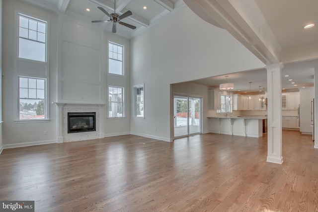 unfurnished living room with ceiling fan, light hardwood / wood-style flooring, and beam ceiling