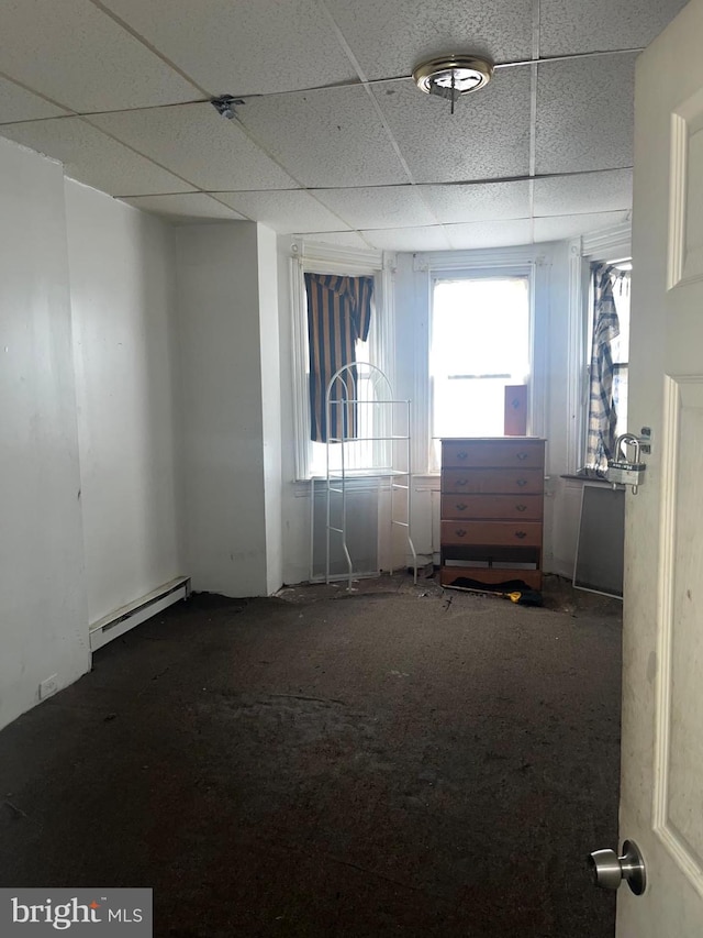 empty room featuring a baseboard radiator and a drop ceiling