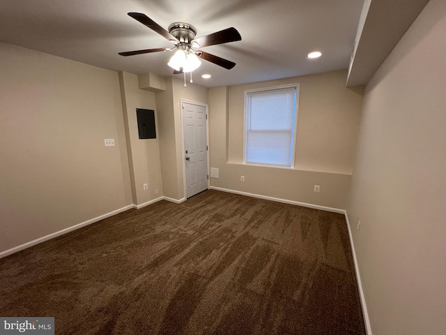 empty room with dark colored carpet, ceiling fan, and electric panel