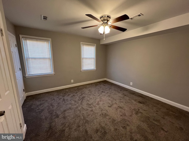 carpeted spare room featuring a wealth of natural light and ceiling fan