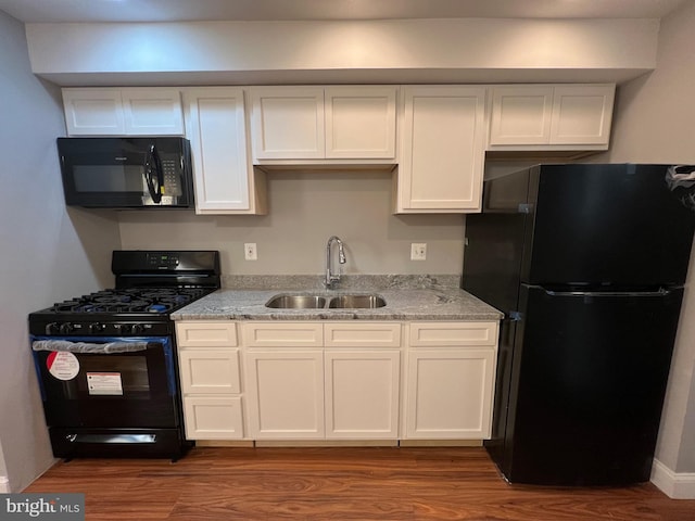 kitchen with black appliances, white cabinetry, and sink