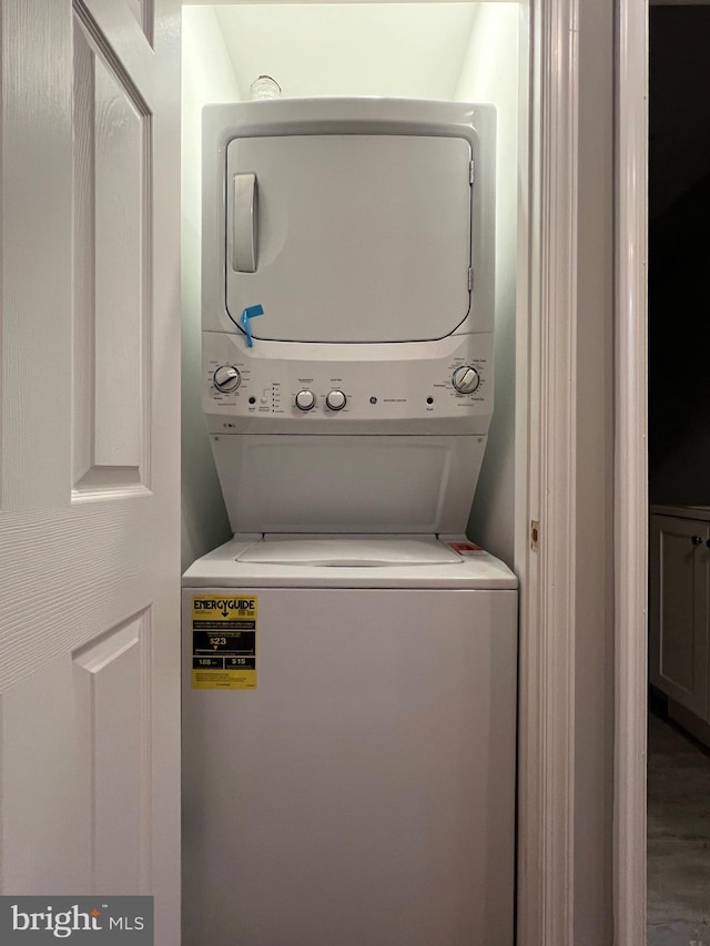 washroom with wood-type flooring and stacked washer / drying machine